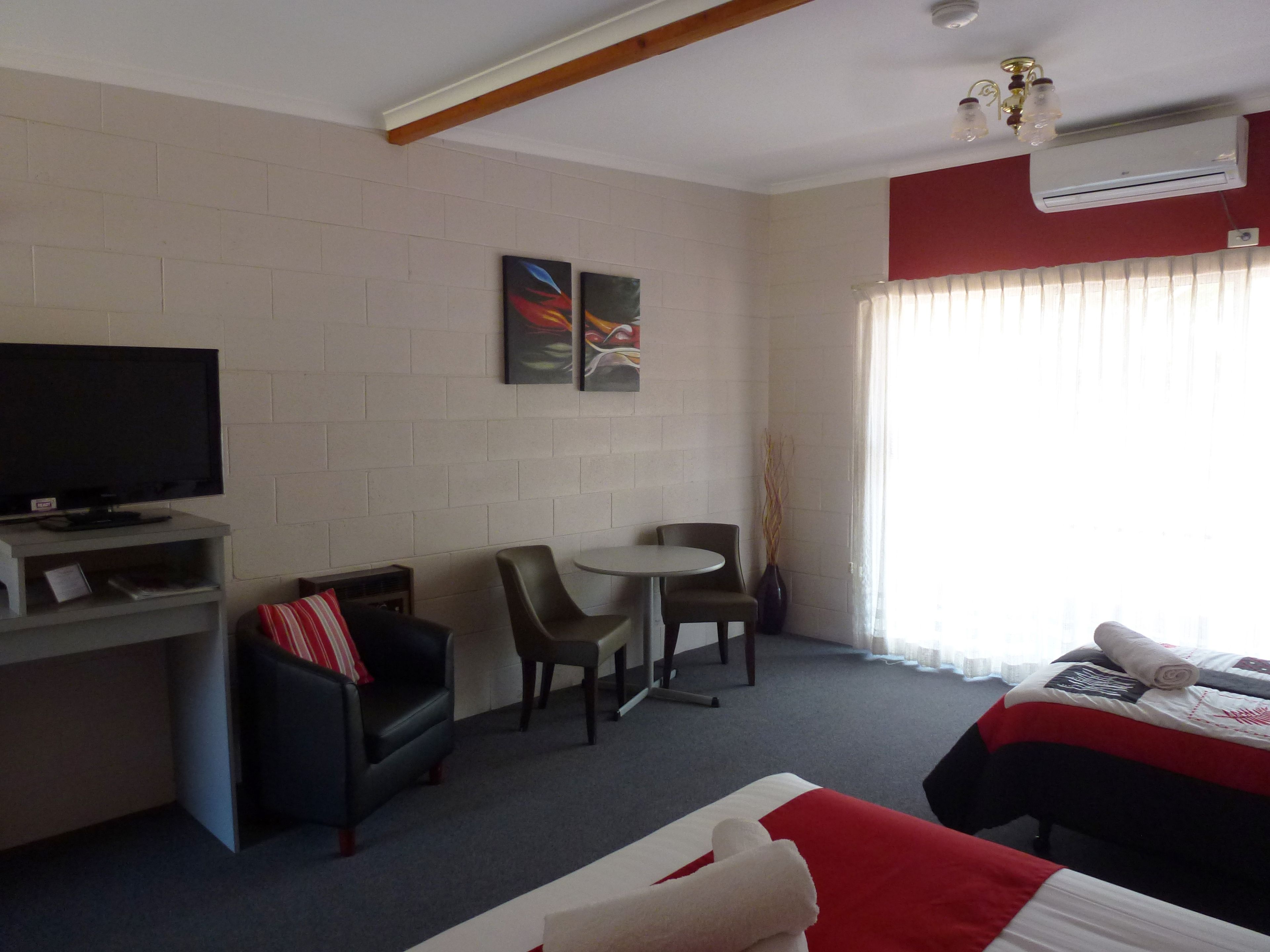 Une chambre d’hôtel avec un lit, une télévision, un bureau, une chaise et une petite table.