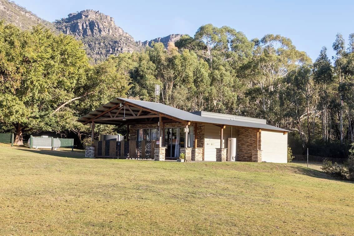 Un bâtiment doté d’un patio couvert, de murs en pierre et offrant une vue sur une montagne.