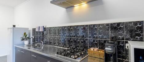 A modern kitchen with a gas stove, coffee maker, and a microwave.