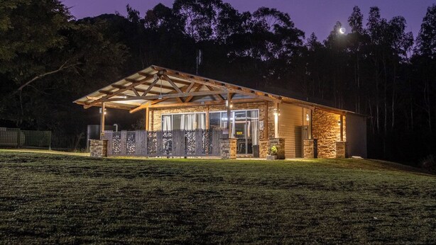 A lodge with a covered outdoor area, stone walls, and a fenced entrance.