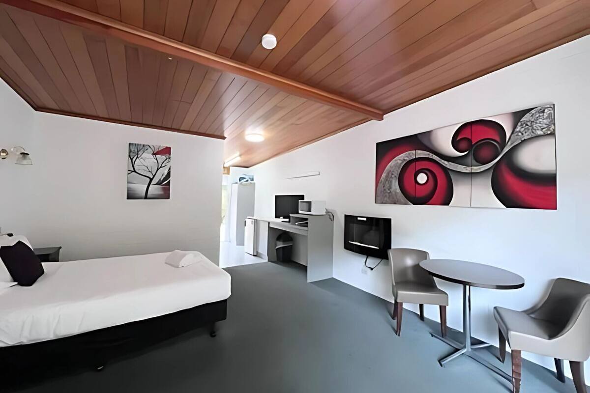 Et moderne hotelværelse med seng, skrivebord, TV og siddeområde.