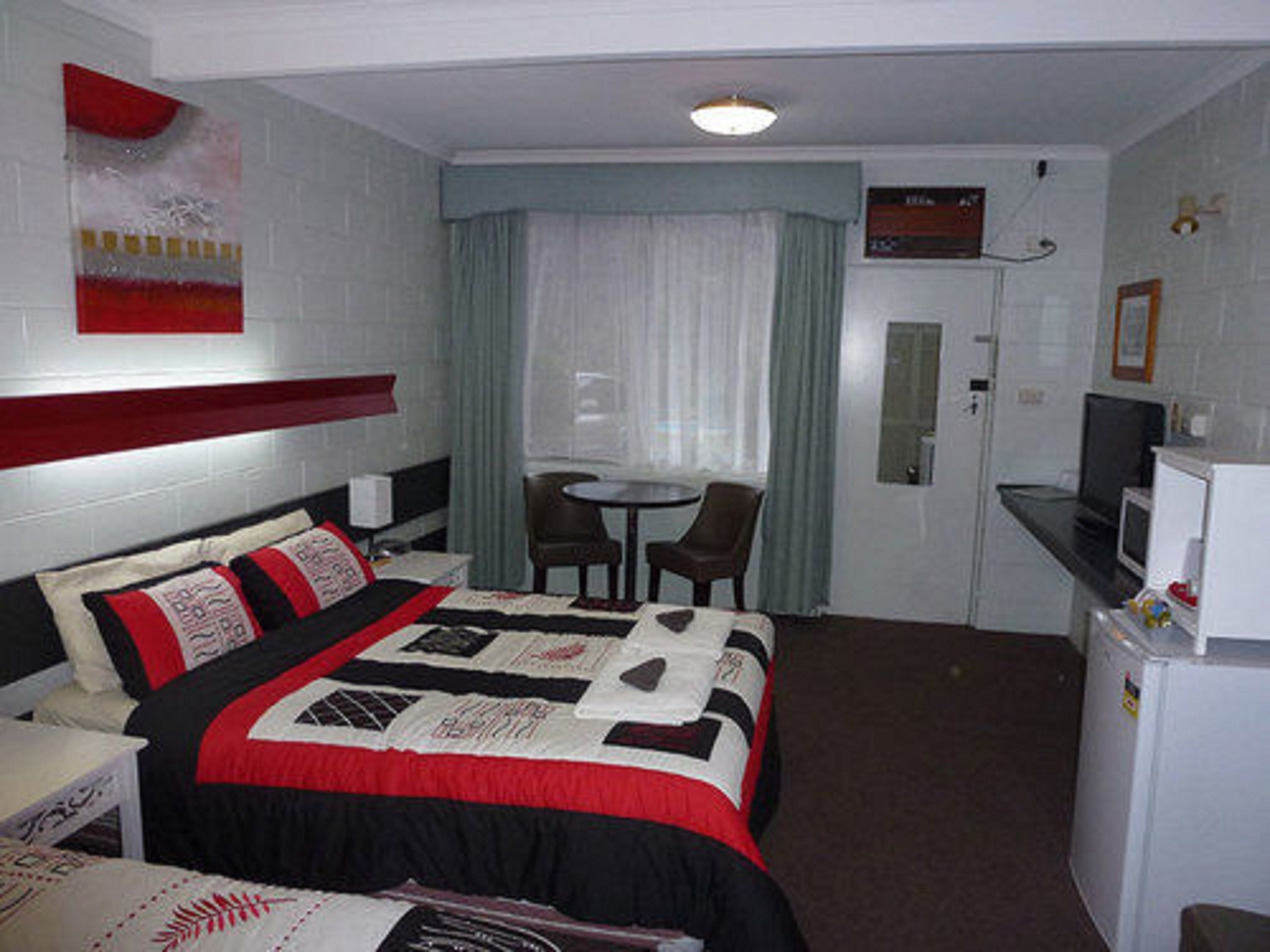 A hotel room with a bed, a desk, a television, and a small dining area.