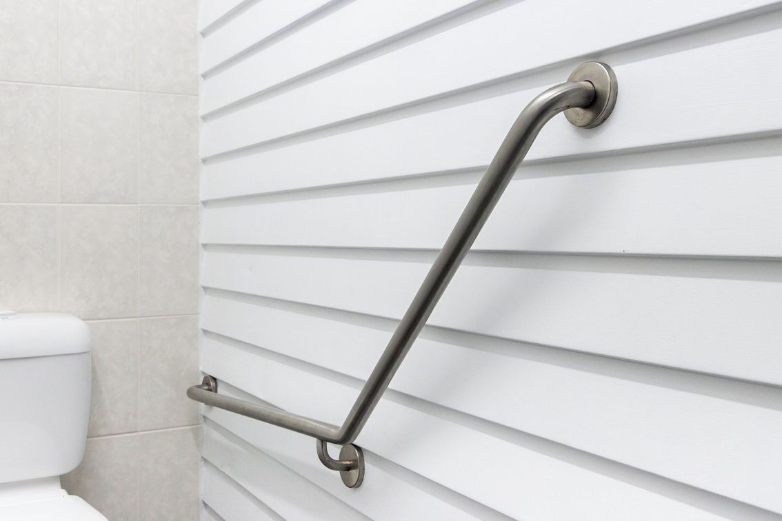 A bathroom with a white toilet and a grab bar installed on the wall.