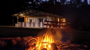 A cabin with a covered porch and a fire pit in front.