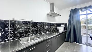 A modern kitchen with black and white marble tiles, stainless steel appliances, and dark cabinetry.