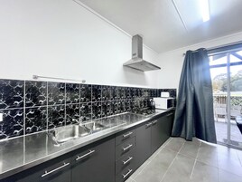 A modern kitchen with black and white marble tiles, stainless steel appliances, and dark cabinetry.