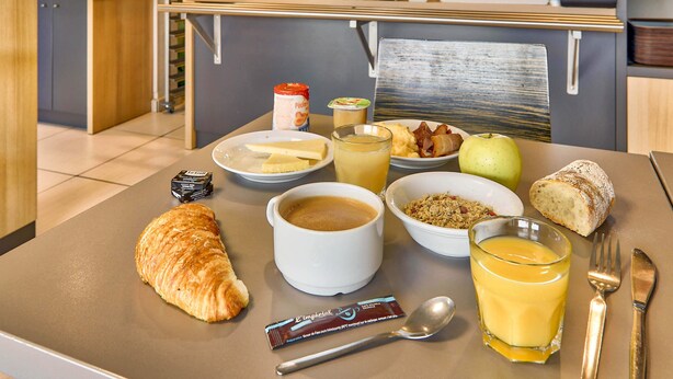 Una mesa de desayuno con cruasanes, café, jugo y un pastel.