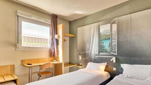 Habitación de hotel con dos camas, un escritorio, una silla, un ventanal con vista a un lago y un cuadro en la pared.