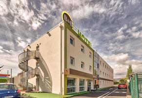 Un hotel con una escalera de caracol, un letrero que dice "B&B HOTEL" y una fachada plana con múltiples ventanas.