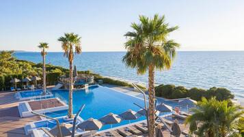 A resort pool with clear blue water, surrounded by palm trees and lounge chairs.