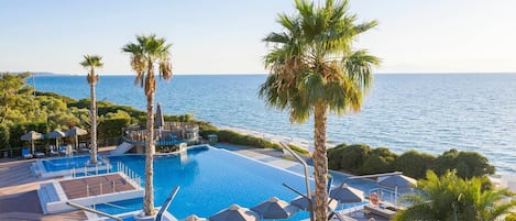 A resort pool with clear blue water, surrounded by palm trees and lounge chairs.
