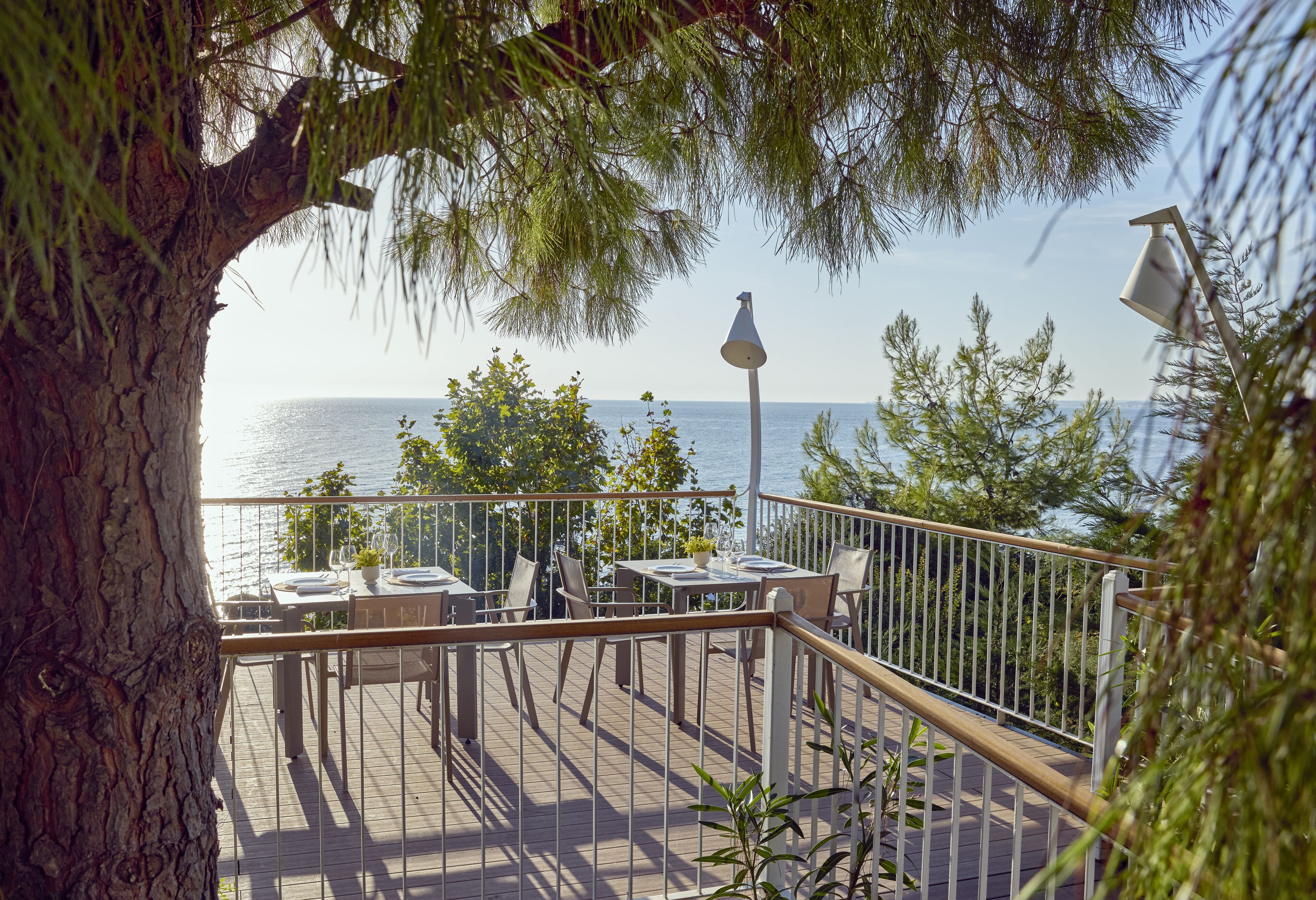 A deck with tables and chairs, overlooking a body of water.