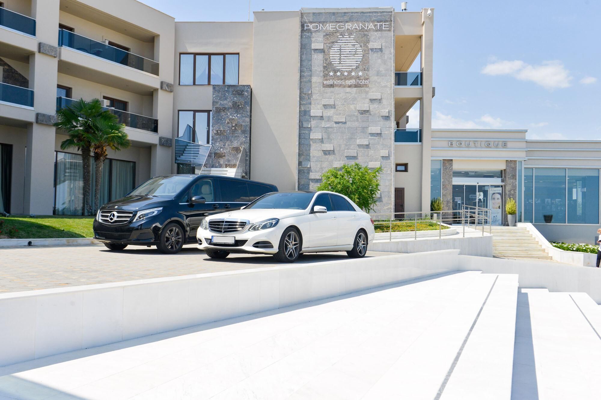 A modern wellness spa hotel with a prominent sign, a boutique, and two luxury cars parked in front.