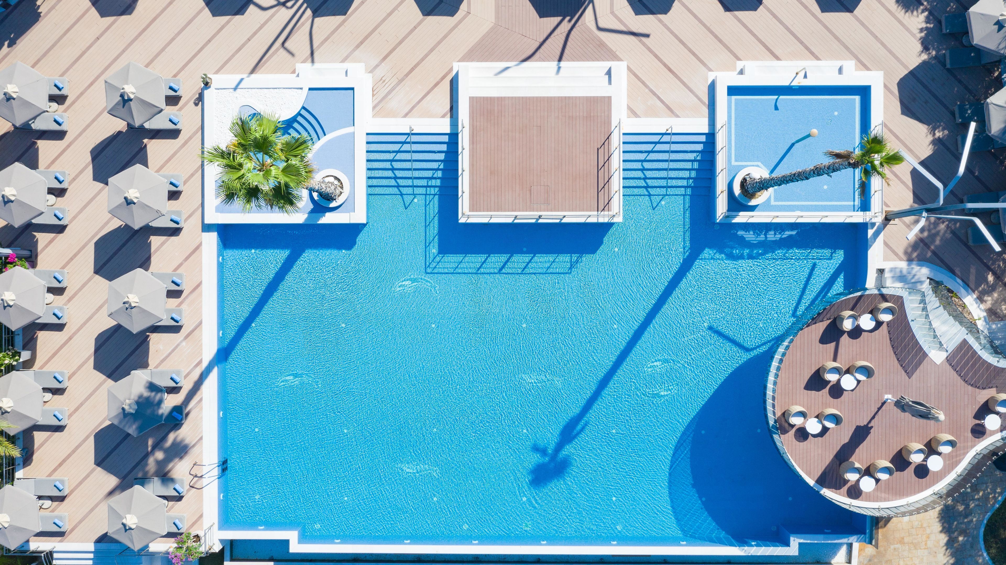 Vue aérienne d’une piscine avec des chaises longues et une zone aménagée autour de la piscine.
