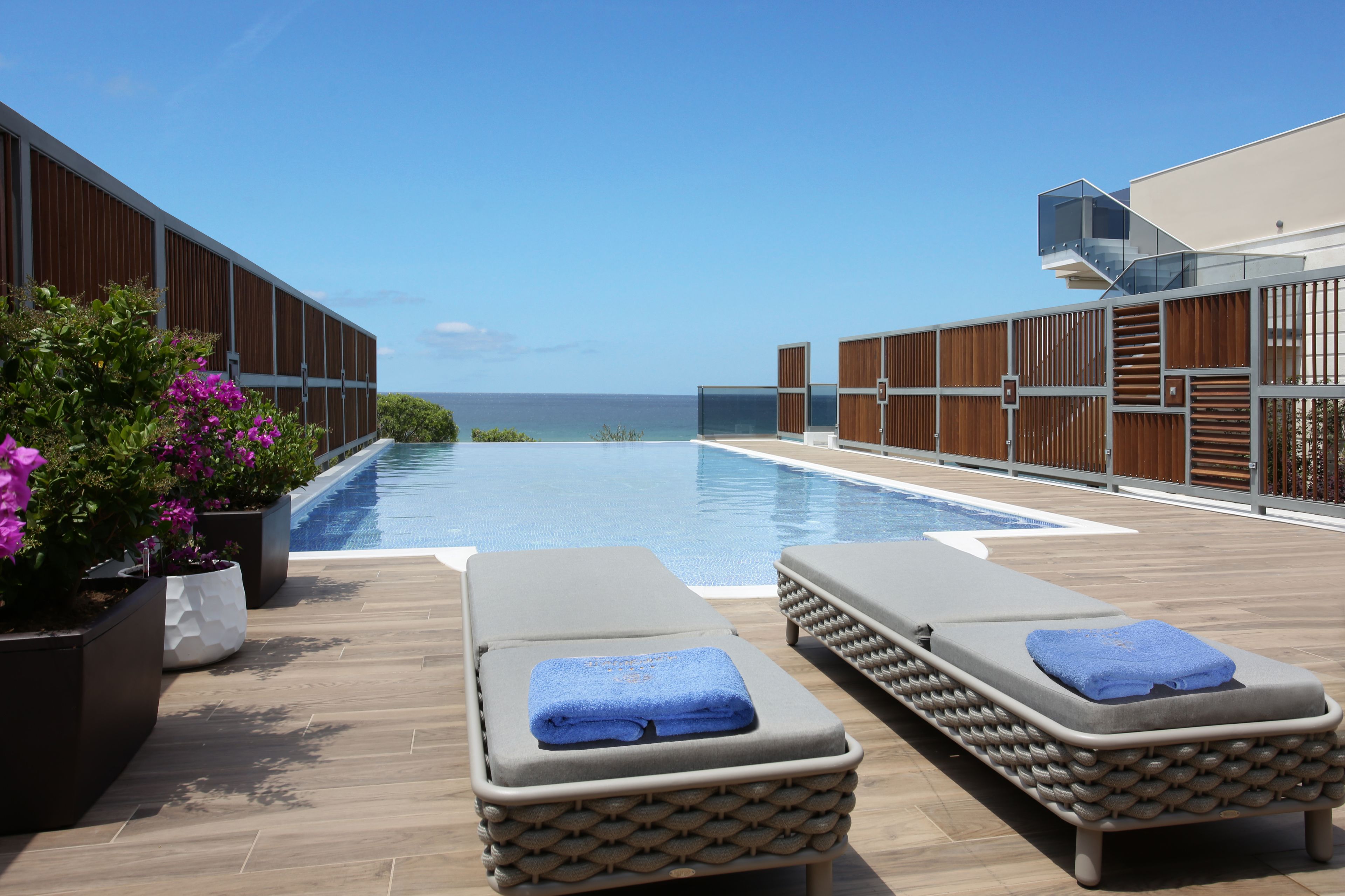 Un área junto a la piscina con sillones de descanso y vista al mar.