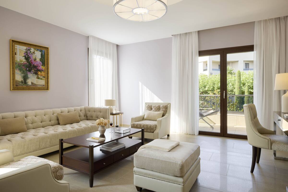 A modern living room with a sofa, armchairs, a coffee table, and a balcony with a view.