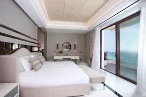 Ein modernes Schlafzimmer mit einem großen Bett, Nachttischen, einem Schminktisch und Meerblick.