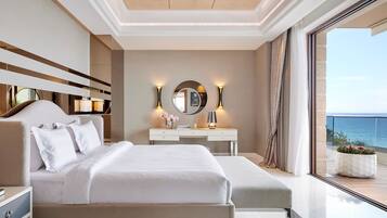Una habitación de hotel moderna con una cama grande, una mesita de noche, un tocador con espejo y vistas al mar.