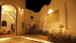 Eine Terrasse im Freien mit Steinboden, einem Tisch mit Stühlen und einer Zierwand.