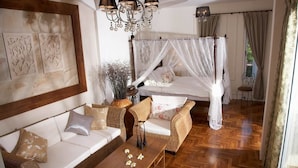 Ein Schlafzimmer mit Himmelbett, einer Couch, einem Couchtisch und einer Wanddekoration.
