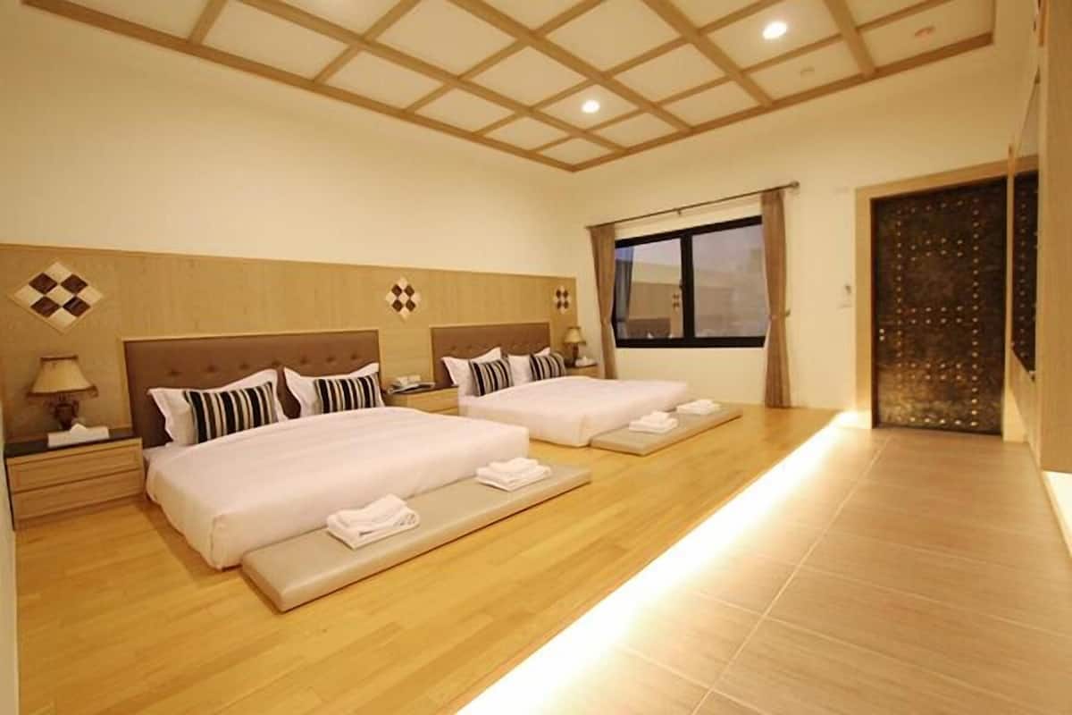 A hotel room with two beds, a large window, and a wooden ceiling.