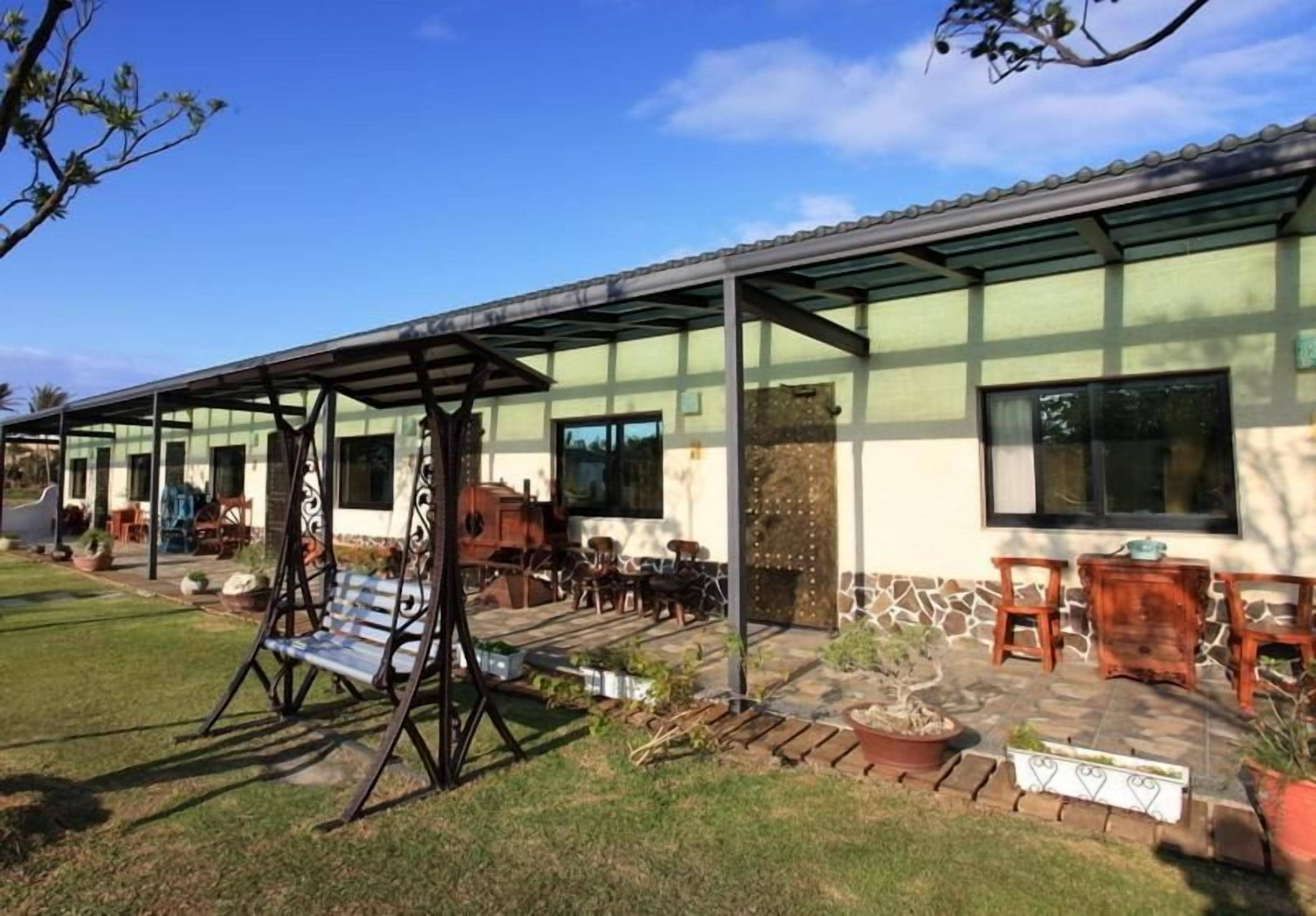 A modern building with a covered patio area, outdoor seating, and a swing chair.