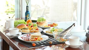 A breakfast buffet with various dishes, a vase with flowers, and a window view.