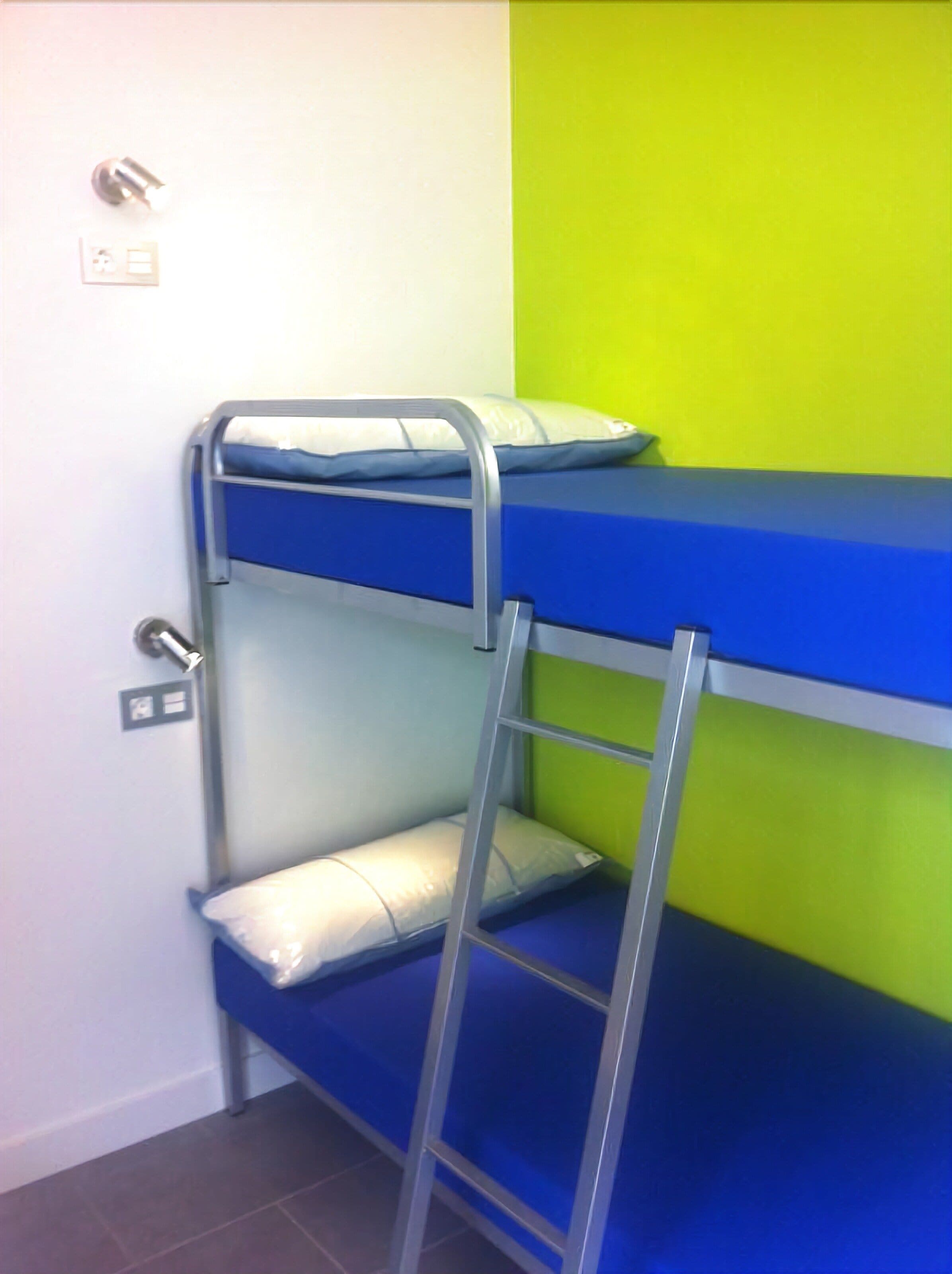 A bunk bed with a ladder, a white wall, and a green wall.