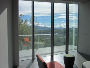 Ein modernes Zimmer mit großen, raumhohen Fenstern und Blick auf eine Berglandschaft.