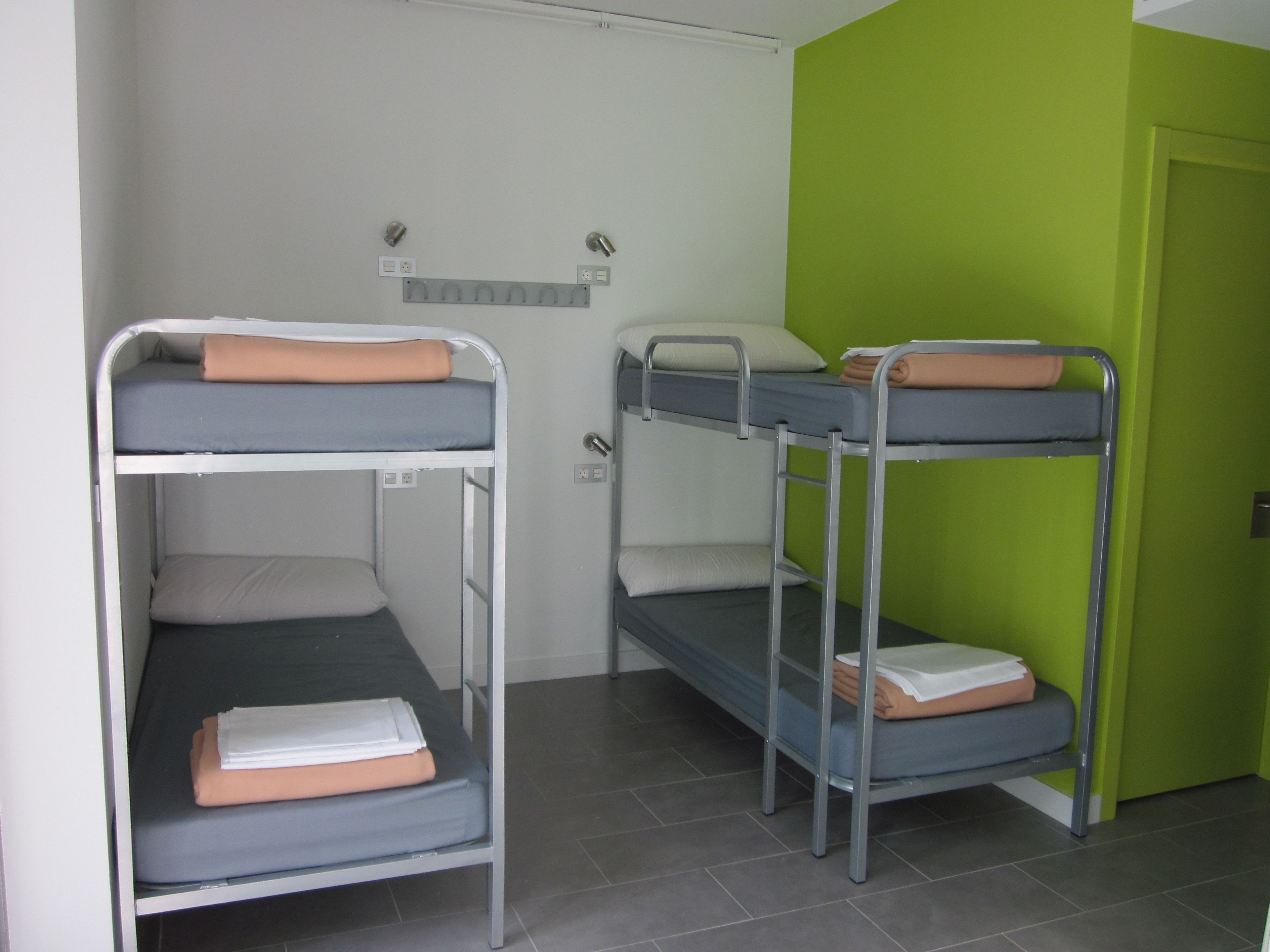 A dormitory room with bunk beds, a green wall, and a door.