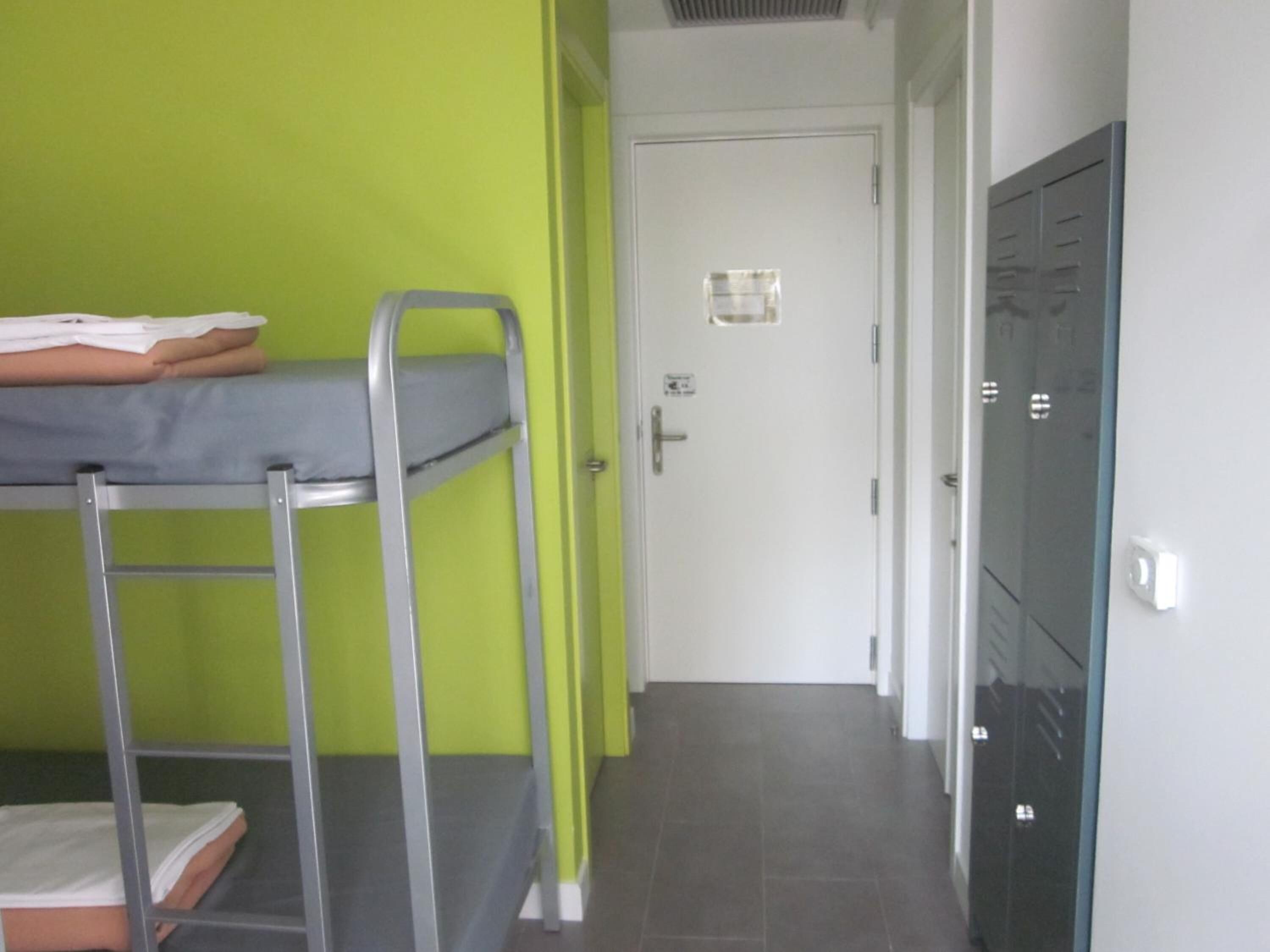 Een kamer met stapelbedden, een deur en een aantal kasten.