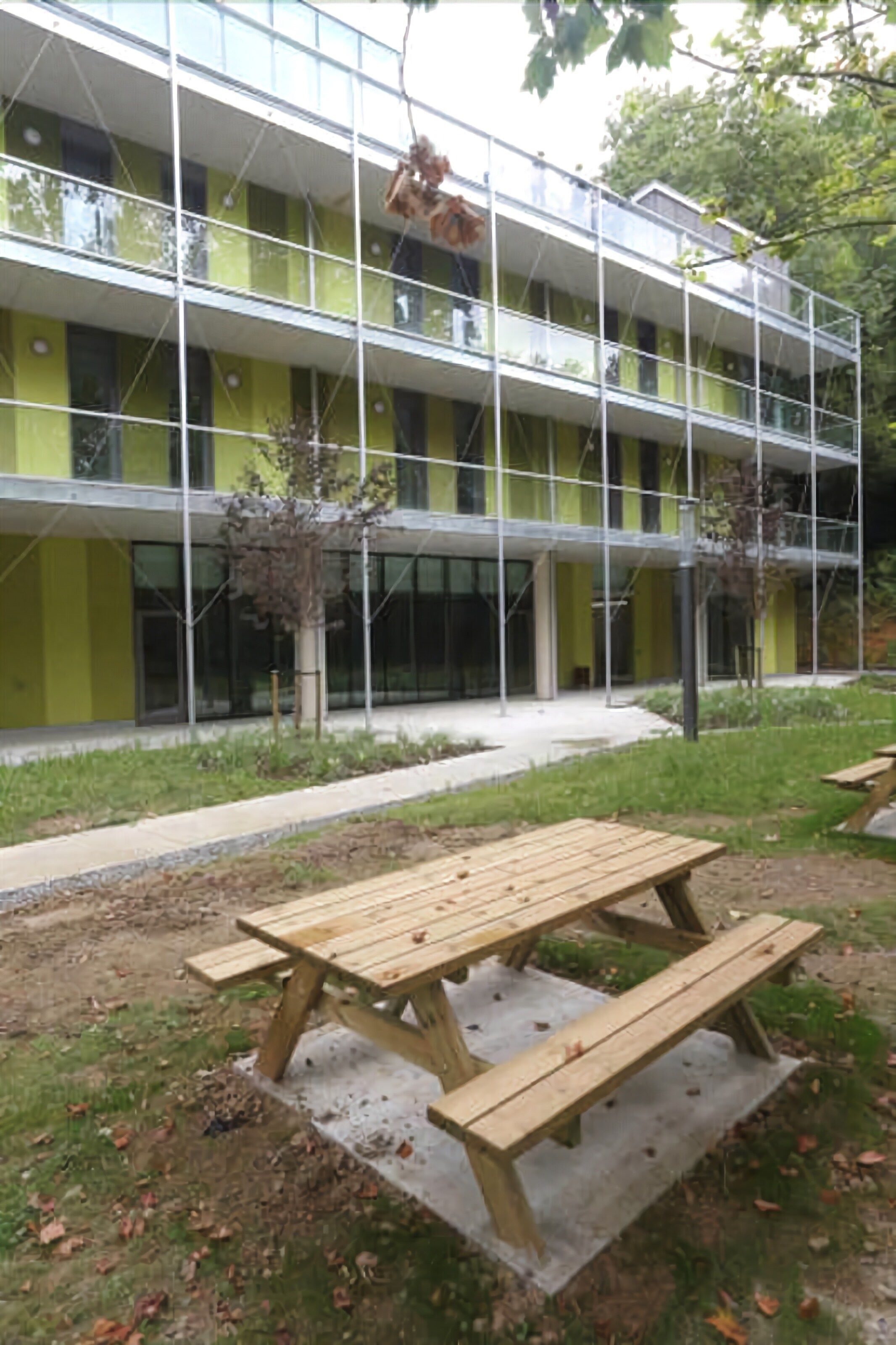 Een modern gebouw met een meerlaagse constructie, een terras en een kleine tuin.