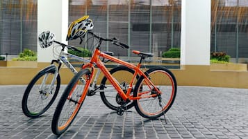 Dos bicicletas estacionadas sobre una superficie pavimentada, con un edificio al fondo.