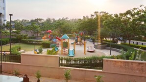 Un parque infantil con toboganes y estructuras para escalar, rodeado de follaje y una valla.