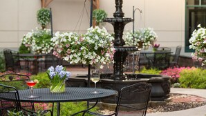 Un patio al aire libre con mesas, sillas, una fuente y arreglos florales.
