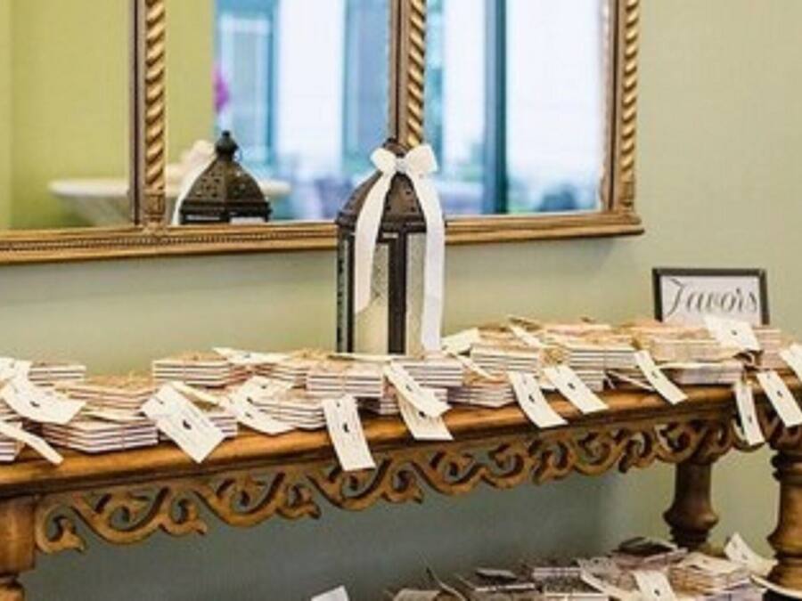 A table with stacks of papers and tags, a mirror, and a chair in a room with green walls.