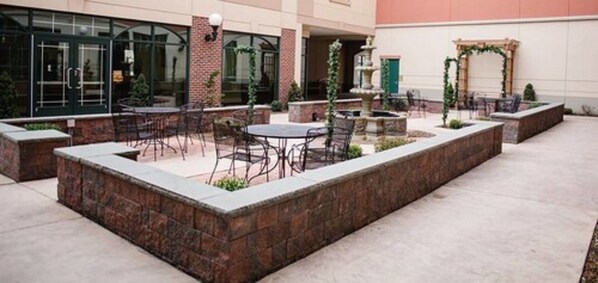 Un patio al aire libre con macetas de piedra, mesas y sillas.