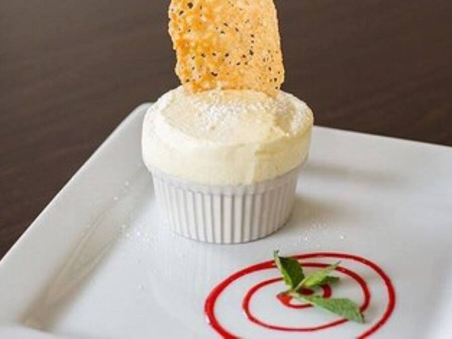 A dessert on a white plate with a red design, a biscuit, and a mint leaf garnish.