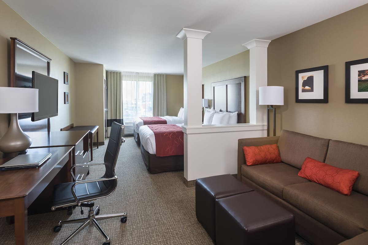 Une chambre d’hôtel équipée d’un bureau, de deux lits, d’un canapé et d’une télévision.