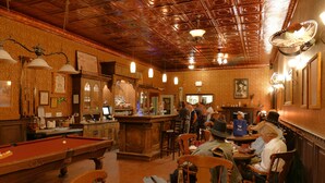 A bar area with a pool table, wooden bar counter, and various bottles and glasses. - Tombstone Monument Guest Ranch (Tombstone)
