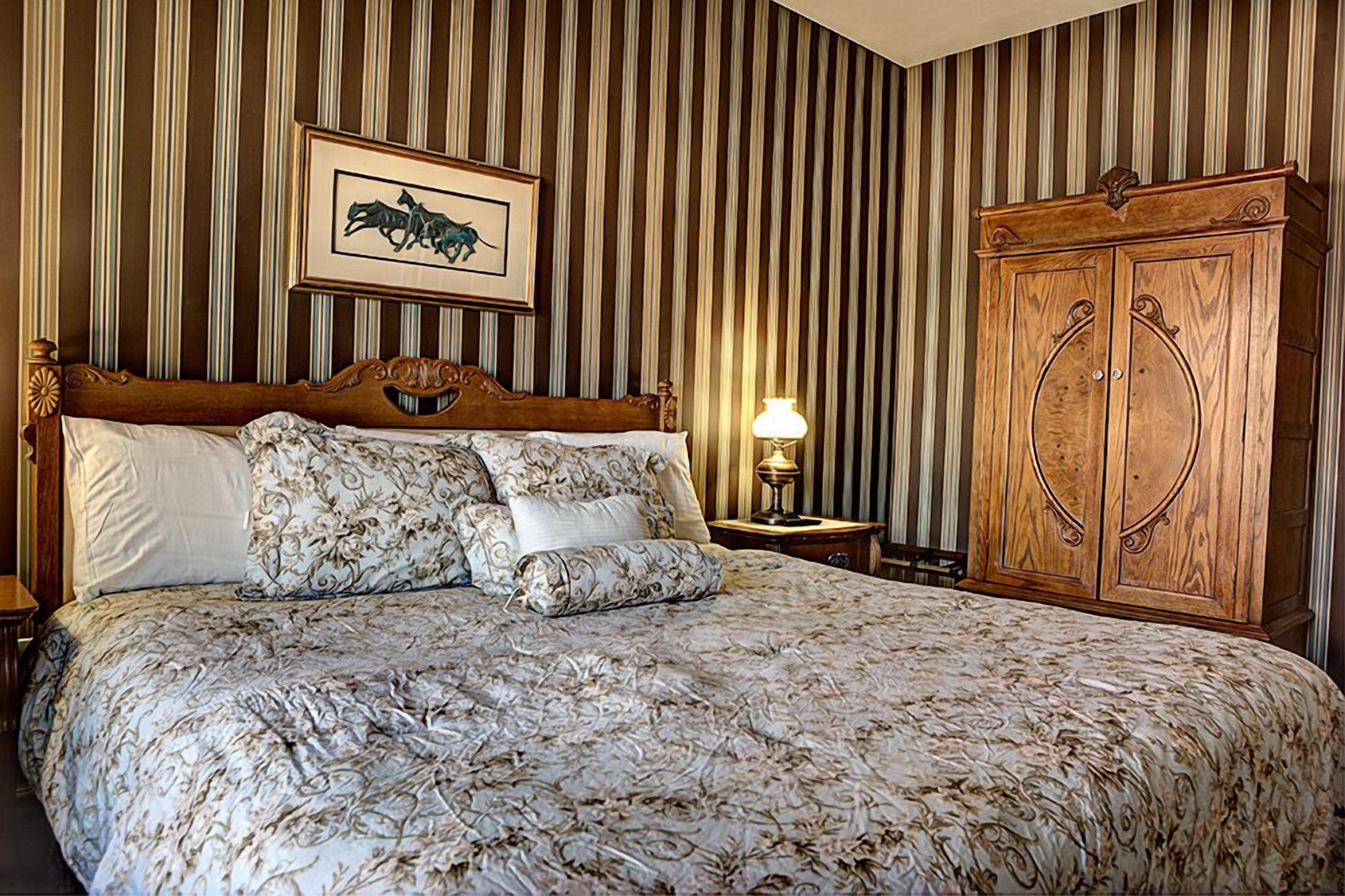 Una habitación de hotel con una cama grande, un armario de madera y un cuadro enmarcado en la pared.