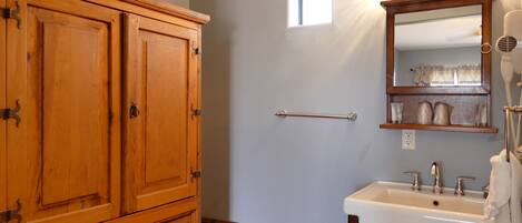 A bathroom with a wooden cabinet, a sink, a mirror, and a towel rack.