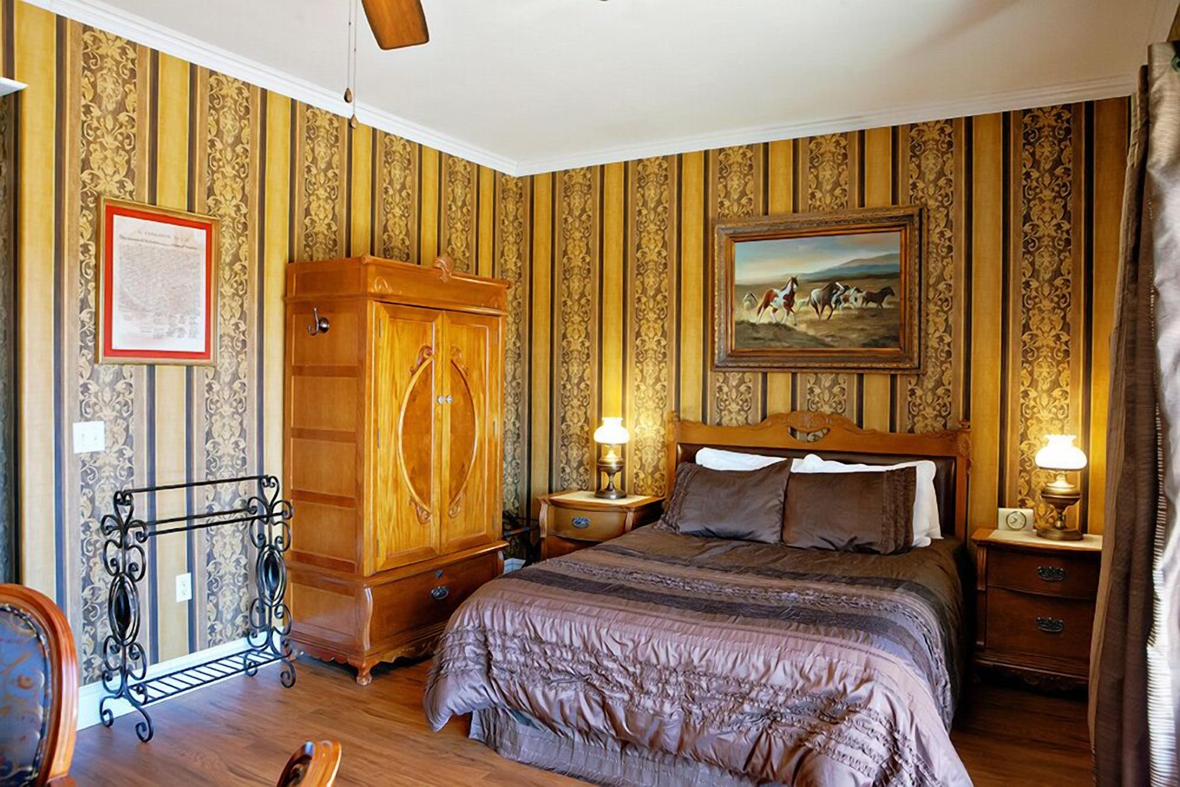 A bedroom with a large bed, wooden wardrobe, and a framed picture on the wall.