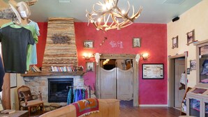 A cozy living room with a fireplace, a mannequin, and a rustic decor style. - Tombstone Monument Guest Ranch (Tombstone)