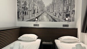 Une chambre d’hôtel avec deux lits, une grande fresque murale et un plancher en bois.