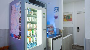 Un distributeur automatique rempli de collations et de boissons, une carte accrochée au mur et un panneau indiquant qu’il est interdit de fumer.