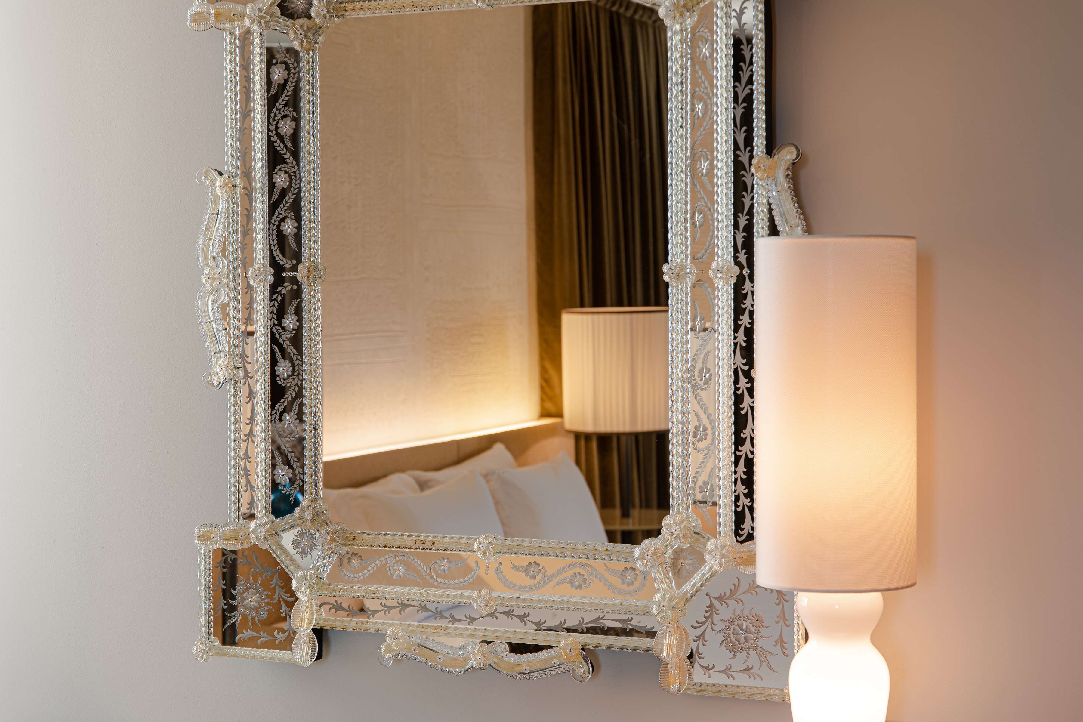 Ein Spiegel mit aufwendigen, verzierten Details und einer weißen Lampe daneben.