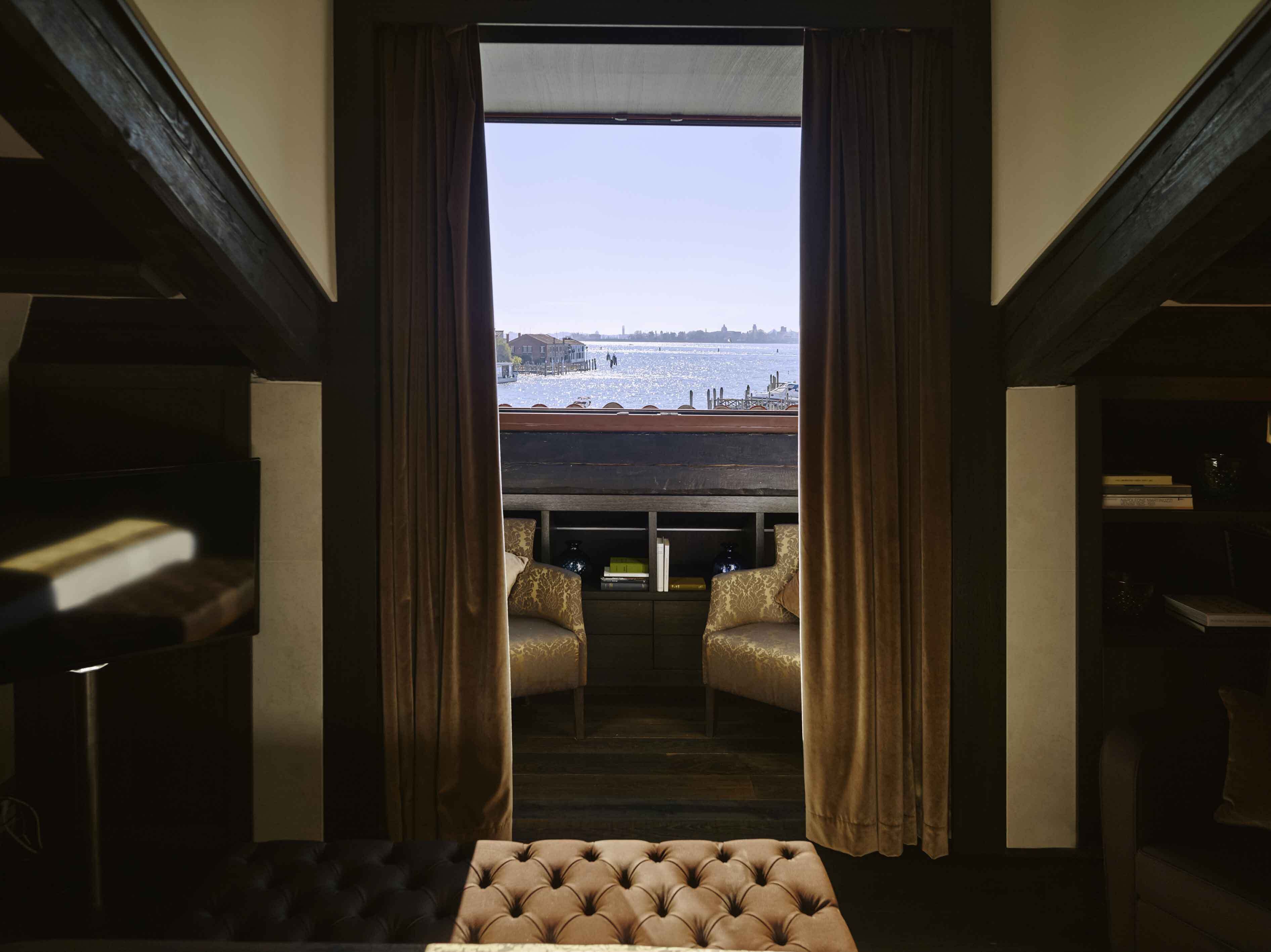 Ein Zimmer mit Blick auf das Wasser, ausgestattet mit einer Couch und einem Tisch mit Büchern.