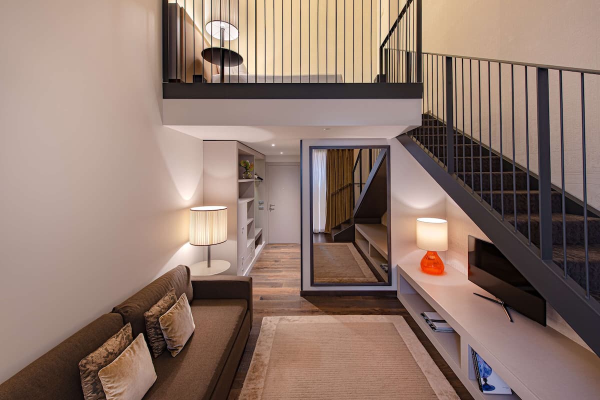 Un intérieur moderne avec un canapé, une console, un escalier et un mur miroitant.