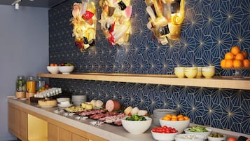 A modern kitchen with a long counter displaying various food items and a decorative wall with geometric patterns.